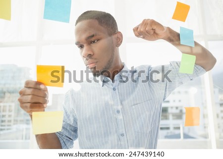 Focused businessman reading sticky notes in the office