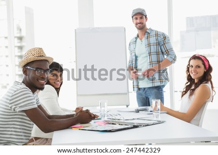 Businessman presenting and smiling colleagues listening in the office