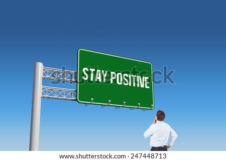 The word stay positive and thinking businessman touching his chin against blue sky