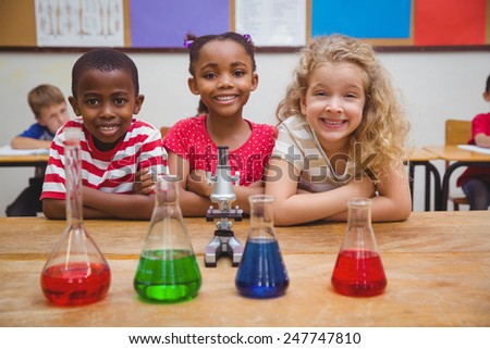 Cute pupils standing with arms crossed behind beaker at the elementary school