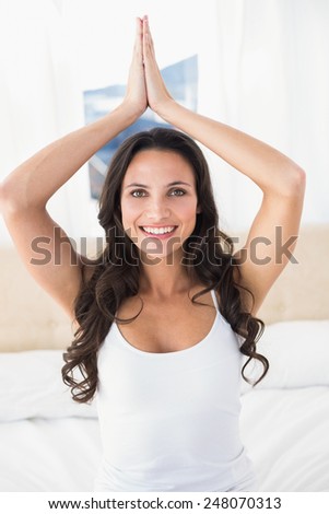 Calm brunette doing yoga on bed at home in bedroom