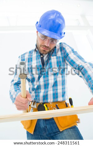 Low angle view of carpenter hitting nail on wooden plank at home