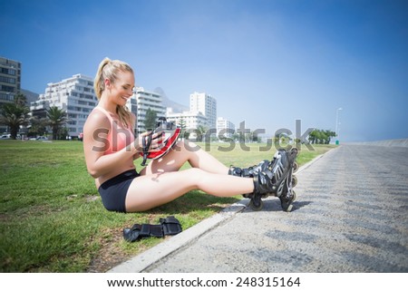 Fit blonde putting on her roller blades on a sunny day