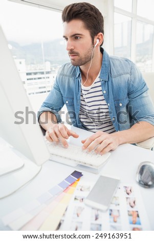 Serious designer enjoying music and typing on keyboard in the office