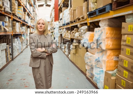 Serious female manager with arms crossed in a large warehouse