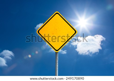yellow sign against bright blue sky with clouds