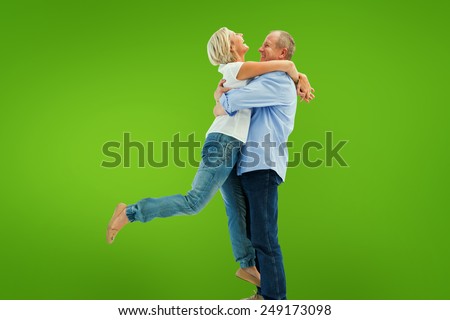 Mature couple hugging and having fun against green vignette