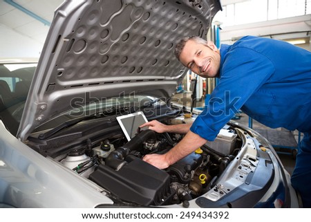 Mechanic using tablet to fix car at the repair garage