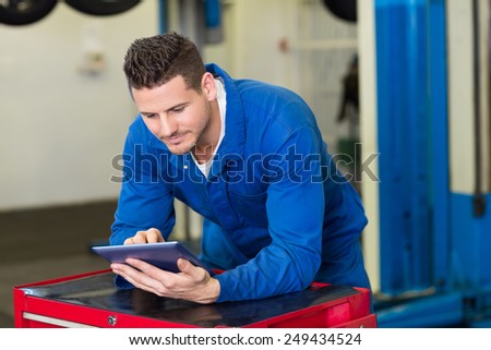 Smiling mechanic using his tablet at the repair garage