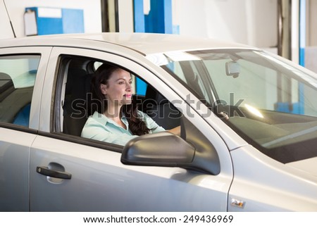Smiling woman in her car at the repair garage