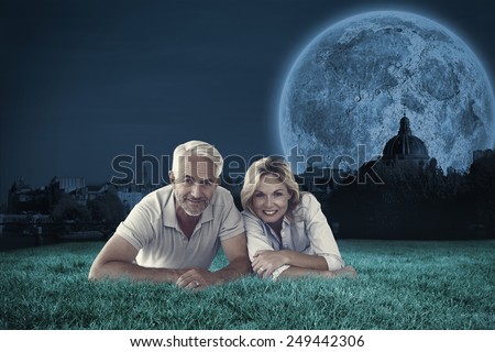 Happy couple lying smiling at camera against bright moon over paris
