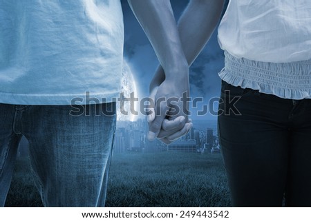 Young couple holding hands in the park against large moon over city