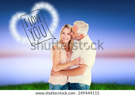 Affectionate man kissing his wife on the cheek against green grass under blue and purple sky