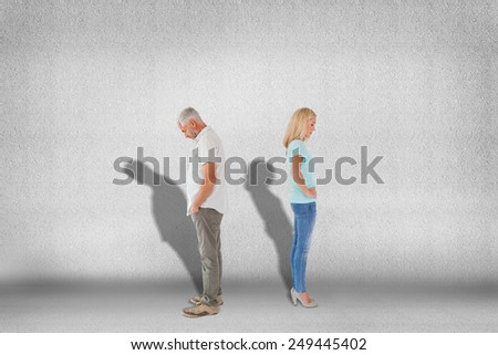 Unhappy couple not speaking to each other against grey wall