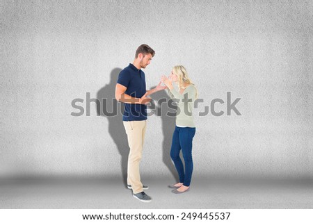Young couple having an argument against grey wall