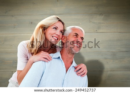 Smiling couple embracing and looking against bleached wooden planks background