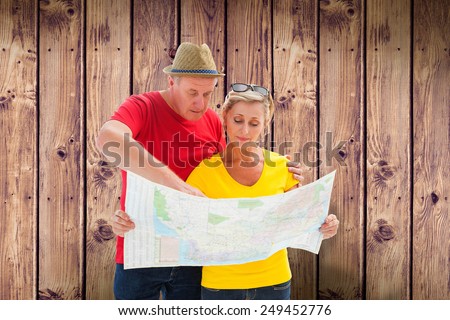 Lost tourist couple using map against wooden planks background