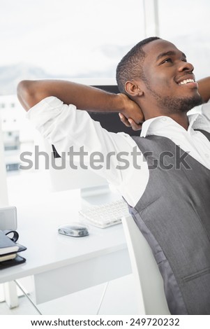 Relaxed businessman with hands behind head in his office