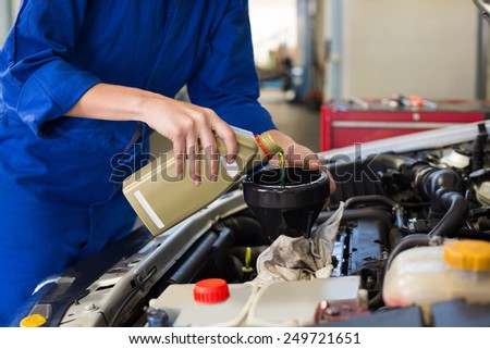 Mechanic pouring oil into car at the repair garage