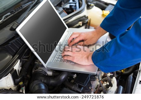 Mechanic using laptop on car at the repair garage