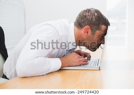 Confused businessman looking at his laptop in his office