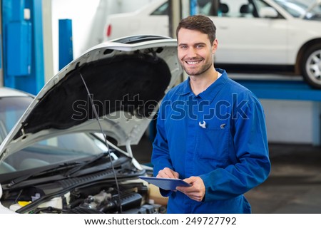 Smiling mechanic using a tablet pc at the repair garage