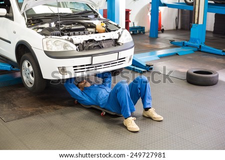 Mechanic lying and working under car at the repair garage