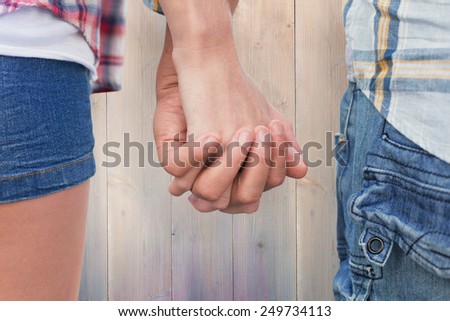 Couple in check shirts and denim holding hands against pale grey wooden planks