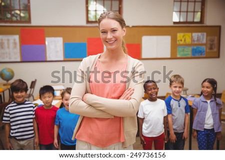 Teacher and pupils smiling at camera in classroom at the elementary school