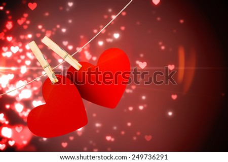 Hearts hanging on line against valentines heart design