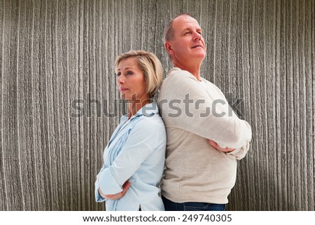 Mature couple standing and thinking against wooden planks