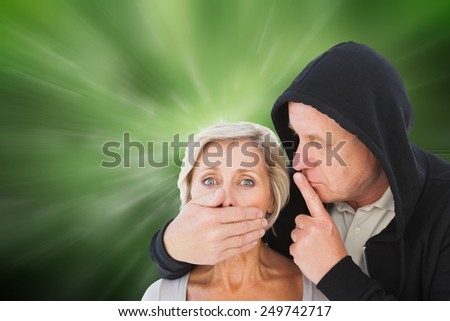 Older man silencing his fearful partner against digitally generated dandelion seeds on green background