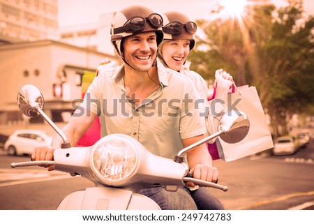 Hip young couple riding scooter with shopping bags on a sunny day in the city