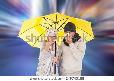 Couple in winter fashion sneezing under umbrella against blurry new york street