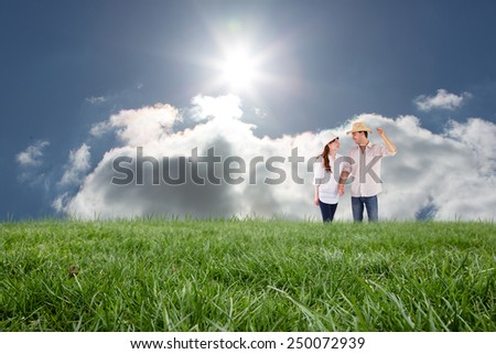 Smiling couple both wearing hats against blue sky with clouds and sun
