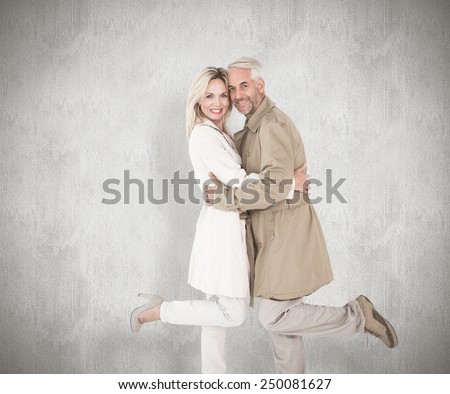 Happy couple posing in trench coats against white background