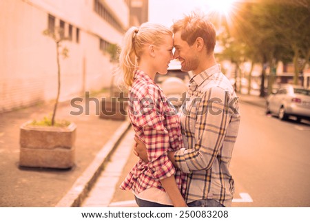 Couple in check shirts and denim hugging each other on a sunny day in the city