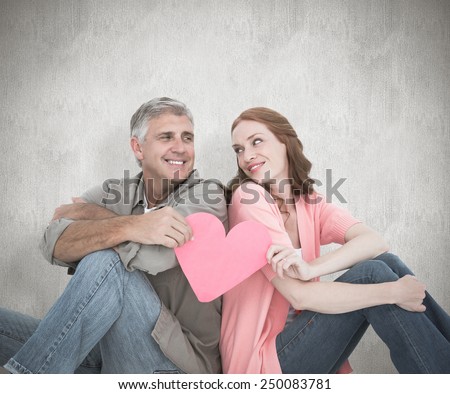 Casual couple holding pink heart against white background
