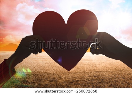 Couple holding a heart against countryside scene