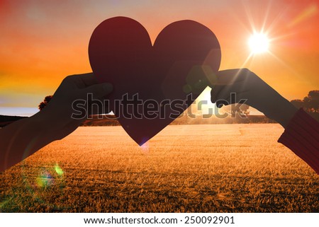 Couple holding a heart against countryside scene
