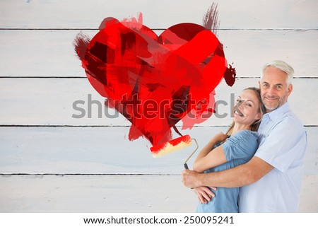 Happy couple hugging and holding paint roller against painted blue wooden planks