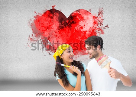 Happy young couple painting together and laughing against grey room