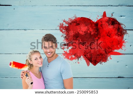 Young couple hugging and holding paint roller against green