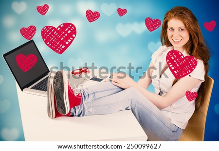 Pretty redhead with feet up on desk against valentines heart design