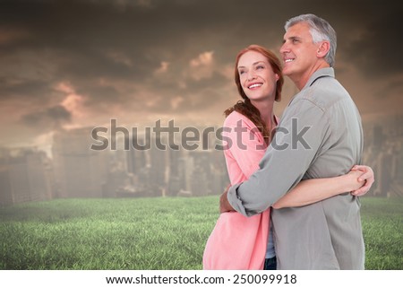Casual couple hugging and smiling against stormy sky over city
