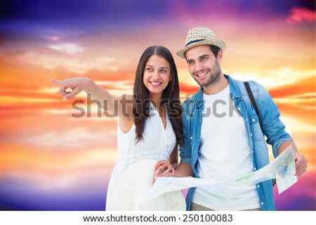 Happy hipster couple looking at map against purple sky with orange clouds