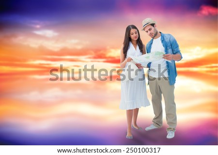 Lost hipster couple looking at map against purple sky with orange clouds