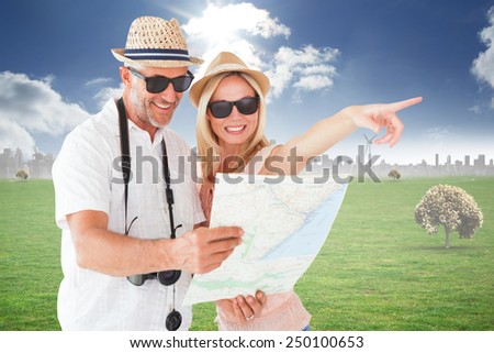 Happy tourist couple using map and pointing against cityscape on the horizon