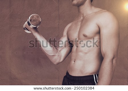 Strong man lifting dumbbell with no shirt on against grey concrete tile
