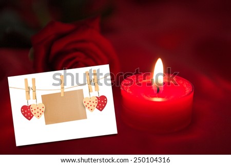 Candle with red rose against white card